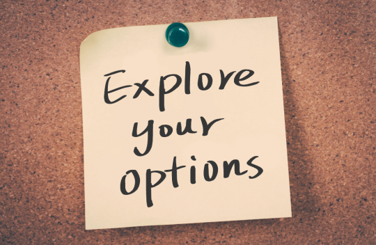 A piece of paper pinned to a notice board that says &#039;explore your options&#039;